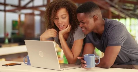 Black millennial couple working together or watching video on laptop in cafe Video stock 69900364
