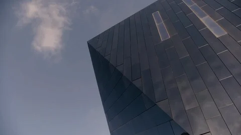 Black Mirrored building detail high tech with wispy cloud in sky pan to right Stock Footage 89944874