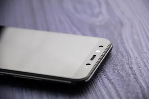 A black modern smartphone with camera. Close up on blue wood table Stock Photos