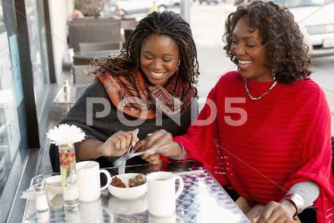 Black Mother And Daughter Having Coffee At Outdoor Cafe