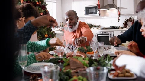 Black multi generation family serving themselves food at their Christmas dinner Stock Footage
