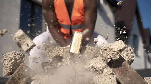 Black muscular builder breaks a building stone into small particles Video stock 128748142