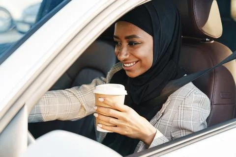 Black muslim woman drinking coffee while driving car Stock Photos