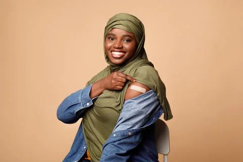 Black Muslim Woman Showing Arm After Coronavirus Vaccination, Beige Background Stock Photos