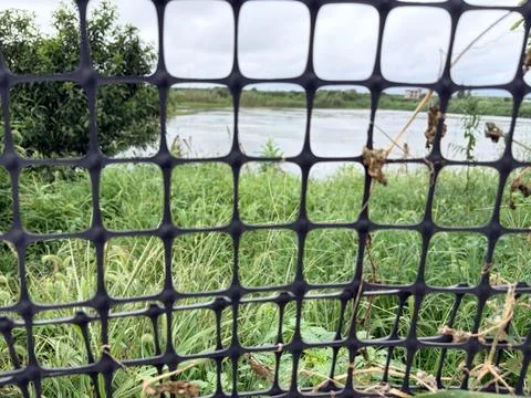 Black net in front of a river and green grass. Stock Photos
