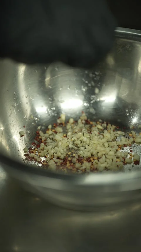 Black Nitrile-Gloved Hand Squeezing Lemon Juice Into Garlic and Chilli Seasoning Stock Footage 345859789
