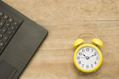Black notebook  and yellow clock on wooden Stock Photos