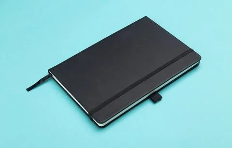 Black notebook isolated on blue background Stock Photos