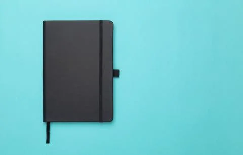 Black notebook isolated on blue background. Flat lay or Top view angle with.. Stock Photos