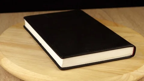 Black notebook rotates 360 degrees on wooden platform Video stock 119492208