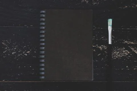 Black notepad on dark desk with brushes Stock Photos
