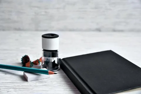Black notepad, pencil sharpener, pencil, elastic on a light background Stock Photos