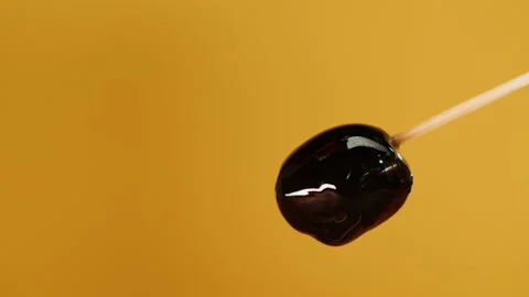 Black olive on yellow background close-up. Falling olive oil drops. Stock Footage 195723262