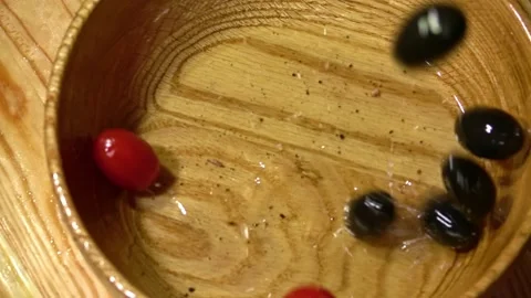 Black olives and cherry tomatoes falling in a wooden bowl Stock Footage 231896865