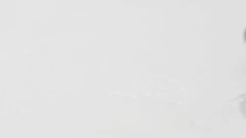 Black olives rolling on a mirror-white surface in slow motion Stock Footage 92857556