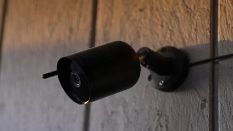 Black outdoor security camera mounted on wooden wall Stock Photos