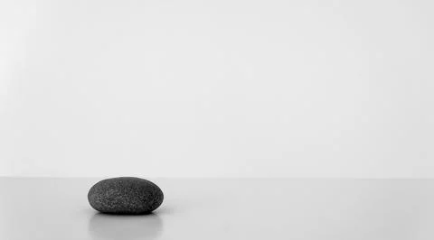 Black oval stone on white table. Concept harmony, balance. Stock Photos