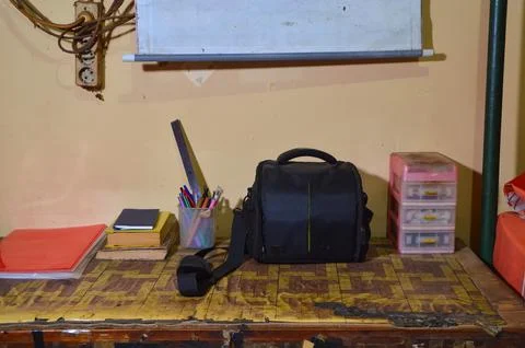 A Black Padded Camera Bag Sitting On A Patterned Study Desk With Stationery 写真素材