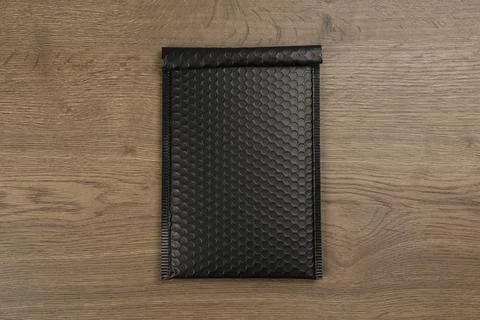 Black padded envelope with bubble wrap on wooden background, top view Stock Photos