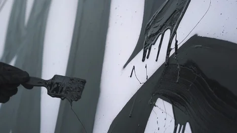 Black paint drips down the canvas. the artist draws. slow motion. Stock Footage 117167762