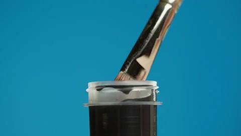 Black paint isolated on blue background. Dark gouache falling from paintbrush Stock-Footage 178604628