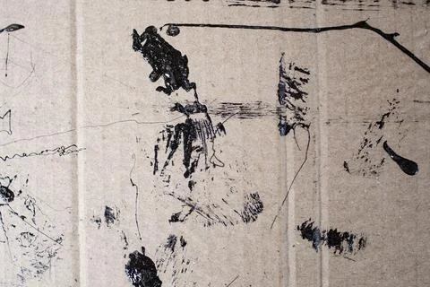 Black paint splashes and  scribbled smudges on brown corrugated cardboard t.. Stock Photos