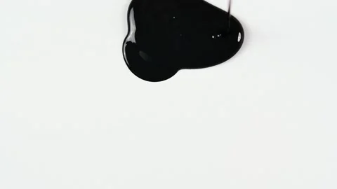 Black paint in a thin stream flows down onto the white surface, forming a Stock Footage 156736004