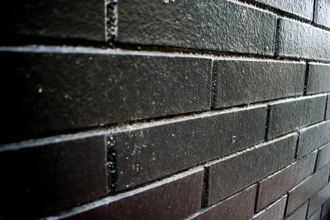 Black Painted Brick Wall with Dramatic Texture and Minimalist Lighting Stock Photos