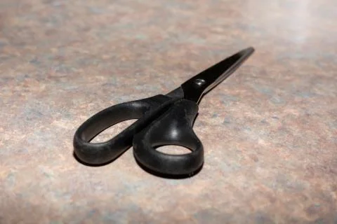 A black pair of scissors lies on the worktop Foto stock