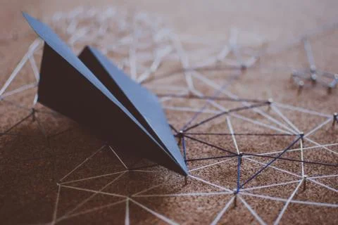 Black paper plane over the threads linking the nails. Entities connected.  Foto stock