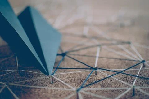 Black paper plane over the threads linking the nails. Entities connected.  Stock Photos