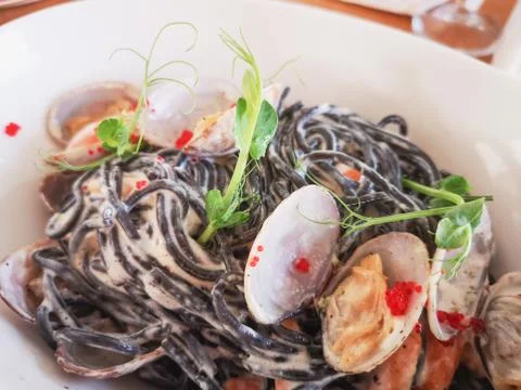 Black paste with cuttlefish ink, with vongol on a white plate. Black spaghett Foto stock
