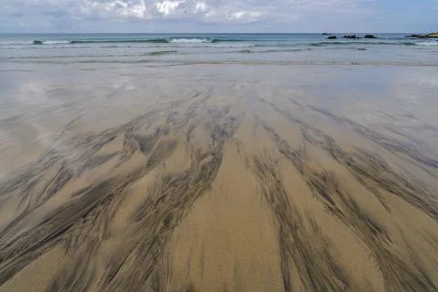 Black patterns and lines on the sand on the beach in St. Ives, Cornwall, Stock Photos
