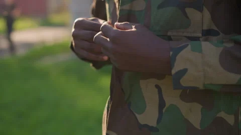 Black Peacekeeper Buttoning Jacket Beside Park Walkway, Soft Morning Light Stock Footage 324759136