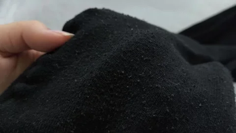 Black pellets, lint on black clothes close-up. Removing pellets from clothes. Stock Footage 316200833