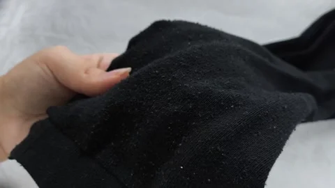 Black pellets, lint on black clothes close-up. Removing pellets from clothes. Stock Footage 316200863
