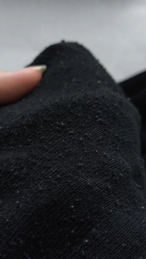 Black pellets, lint on black clothes close-up. Removing pellets from clothes. Stock Footage 316200880