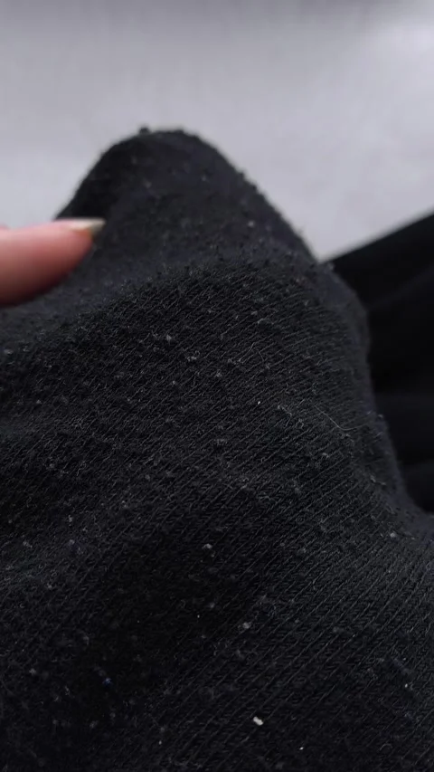 Black pellets, lint on black clothes close-up. Removing pellets from clothes. Stock Footage 316200983