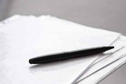 Black pen on documents on a gray table Stock Photos