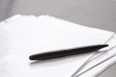 Black pen on documents on a gray table Stock Photos