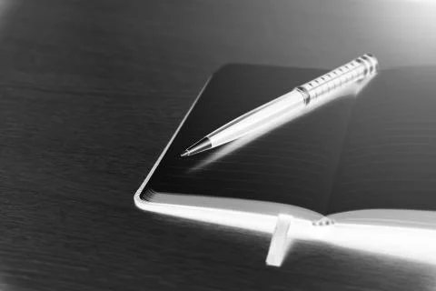 Black pen lies on the opened note cover on the spring on a light wooden table Stock Photos