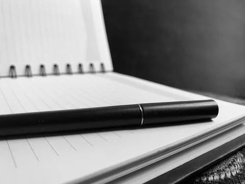 Black Pen Resting Horizontally on Open Spiral Notebook Black and White Macro Stock Photos