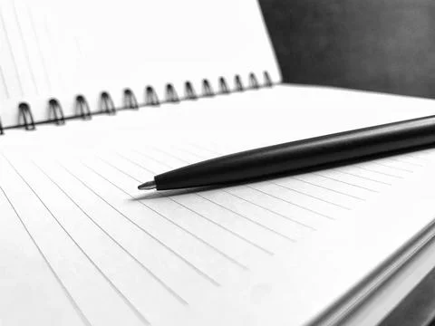 Black Pen Resting Horizontally on Open Spiral Notebook Black and White Macro Stock Photos