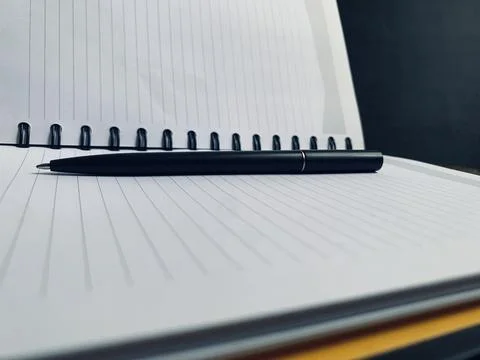 Black Pen Resting Horizontally on Open Lined Spiral Notebook Close Up Macro View Stock Photos