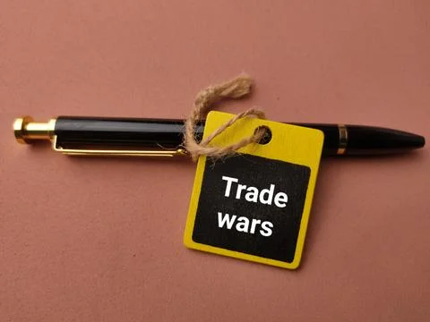 A black pen is tied with string to a tag reading Trade wars on a pinkish ba.. Stock Photos