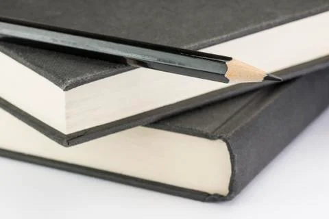 Black pencil on two black write books. Stock Photos