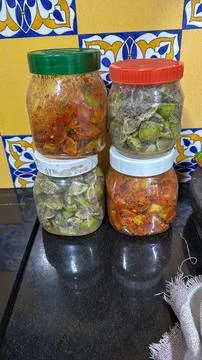 Black pepper and red chilli powder lemon pickle kept in separate bottles on.. Stock Photos