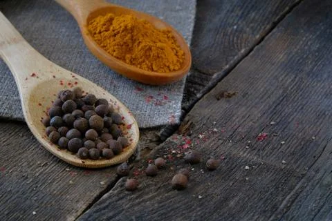 Black pepper and turmeric on a wooden spoon on the background of the old tabl Stock Photos