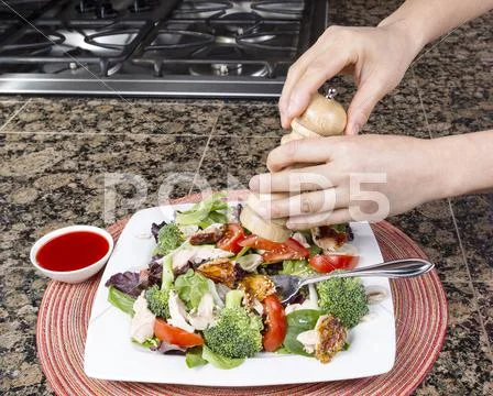 Black pepper being added to salad Stock Photos