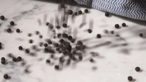 Black pepper falling and bouncing on a marble table Video stock 115772263